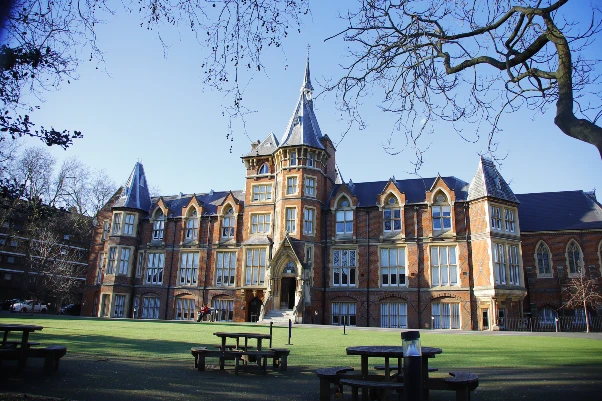 Здание английской школы в викторианском стиле в Лондоне. Из красного кирпича с центральной башенкой и большими окнами.