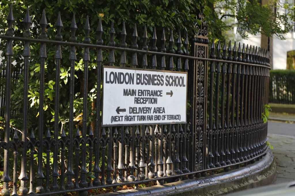 Табличка лондонской школы бизнеса с надписью черными буквами "London Business School". Весит на металлическом черном заборе школы.